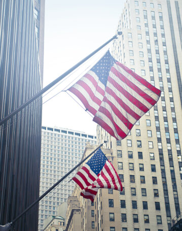 A shot of two American or US flags on a high rise building