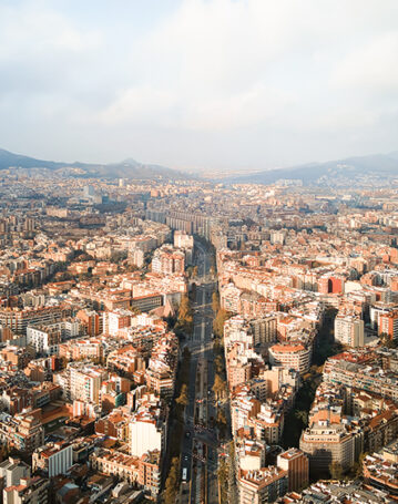 Aerial drone view of Barcelona, Spain. Blocks with multiple residential and office buildings, streets with greenery and cars